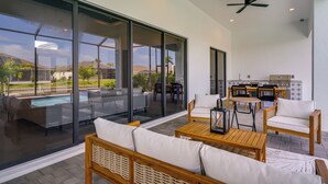 Une terrasse extérieure moderne, dotée d’une piscine, d’un espace salon et d’un coin cuisine.