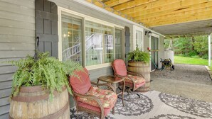 A covered porch with wicker chairs and a large potted plant. - Searsport Paradise w/ Private Pool & Patio! (Searsport)
