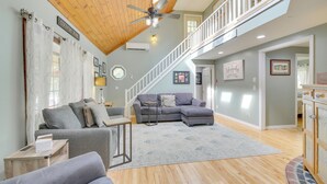 A spacious living area with a wooden ceiling, a grey sectional sofa, a small table, and a staircase leading to an upper level. - Searsport Paradise w/ Private Pool & Patio! (Searsport)