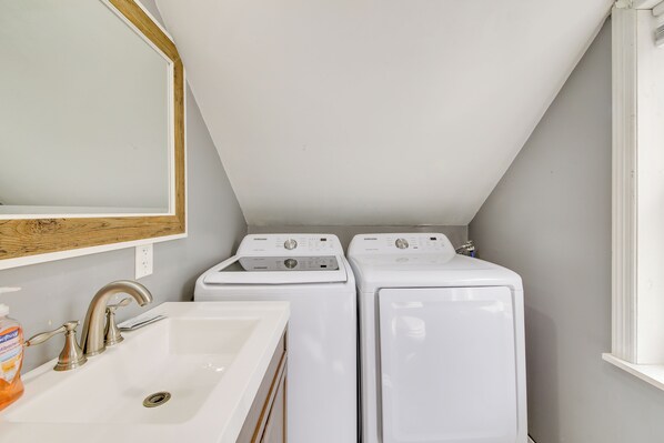 A compact laundry room with two white front-loading washing machines and a sink with a faucet. - Searsport Paradise w/ Private Pool & Patio! (Searsport)