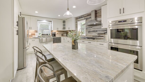 A modern kitchen with white cabinetry, stainless steel appliances, a marble island, and pendant lighting. - Searsport Paradise w/ Private Pool & Patio! (Searsport)