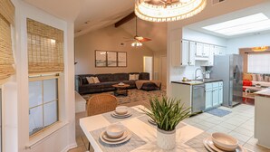 Une cuisine moderne avec des meubles blancs, un réfrigérateur en acier inoxydable et un coin repas avec une table dressée pour deux personnes.
