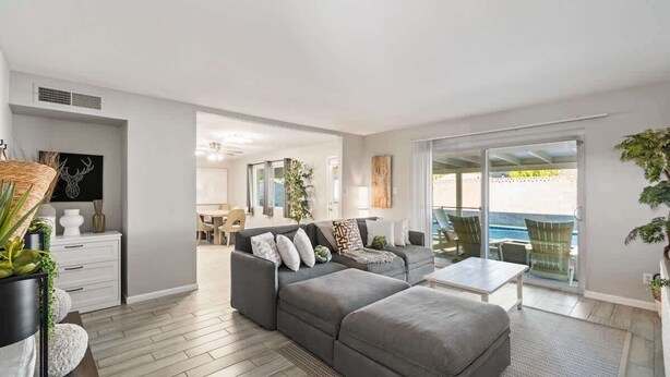 Een moderne woonkamer met een grijze modulaire bank, een klein tafeltje en uitzicht op de oceaan door grote schuifdeuren.