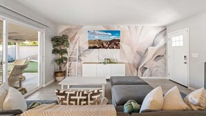 Een moderne woonkamer met een grote flatscreen televisie, een grijze bank en een witte salontafel.