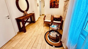 Un couloir avec un banc en bois, un miroir, des chaises en osier et un panier en osier contenant des magazines.
