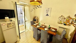 Une cuisine compacte équipée d’un réfrigérateur, d’un four à micro-ondes et d’un coin repas avec des chaises à rayures et une table en bois.
