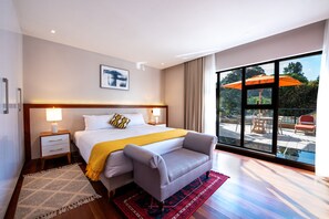 Une chambre d’hôtel moderne dotée d’un grand lit, d’un canapé, d’une table de chevet et offrant une vue sur la terrasse extérieure.