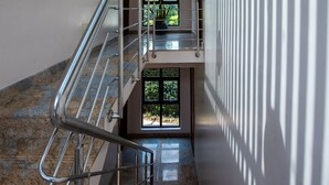 Un interior moderno con techo de madera, una escalera de metal y vistas a la vegetación exterior.