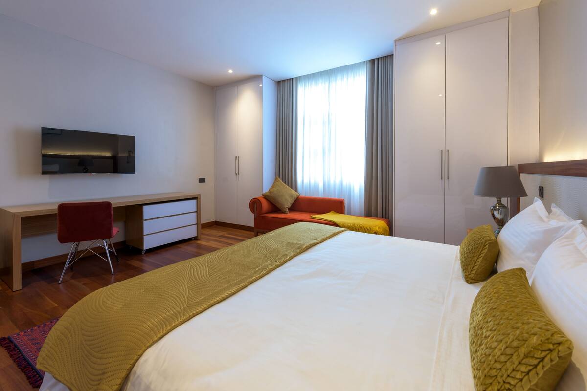 Een moderne hotelkamer met een groot bed, een bureau met stoel, een televisie en een kledingkast.
