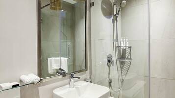 A modern bathroom with a glass shower enclosure, a large mirror, and a glass-topped sink.