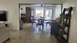 A dining area with a table and chairs, a kitchen with a microwave, and a TV mounted on the wall.
