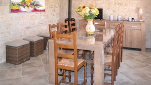 A dining area with a long wooden table, wicker chairs, and a vase with flowers. - Maison de Campagne "monplaisir" en Quercy Blanc (Montlauzun)