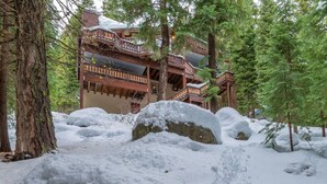 A wooden cabin with a balcony, surrounded by snow-covered trees and rocks. - Tahoe Donner w/ Private Hot Tub (Truckee)