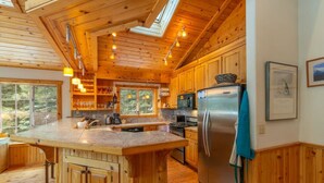 A spacious kitchen with wooden cabinets, a large island, and a stainless steel refrigerator. - Tahoe Donner w/ Private Hot Tub (Truckee)