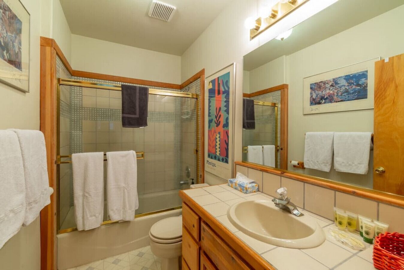 A bathroom with a shower, toilet, sink, and large mirror.