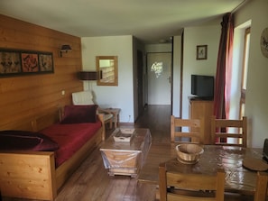 A wooden-furnished living room with a sofa, a small table, and a TV. - Studio 2 - Double Exposition (Brides-les-Bains)
