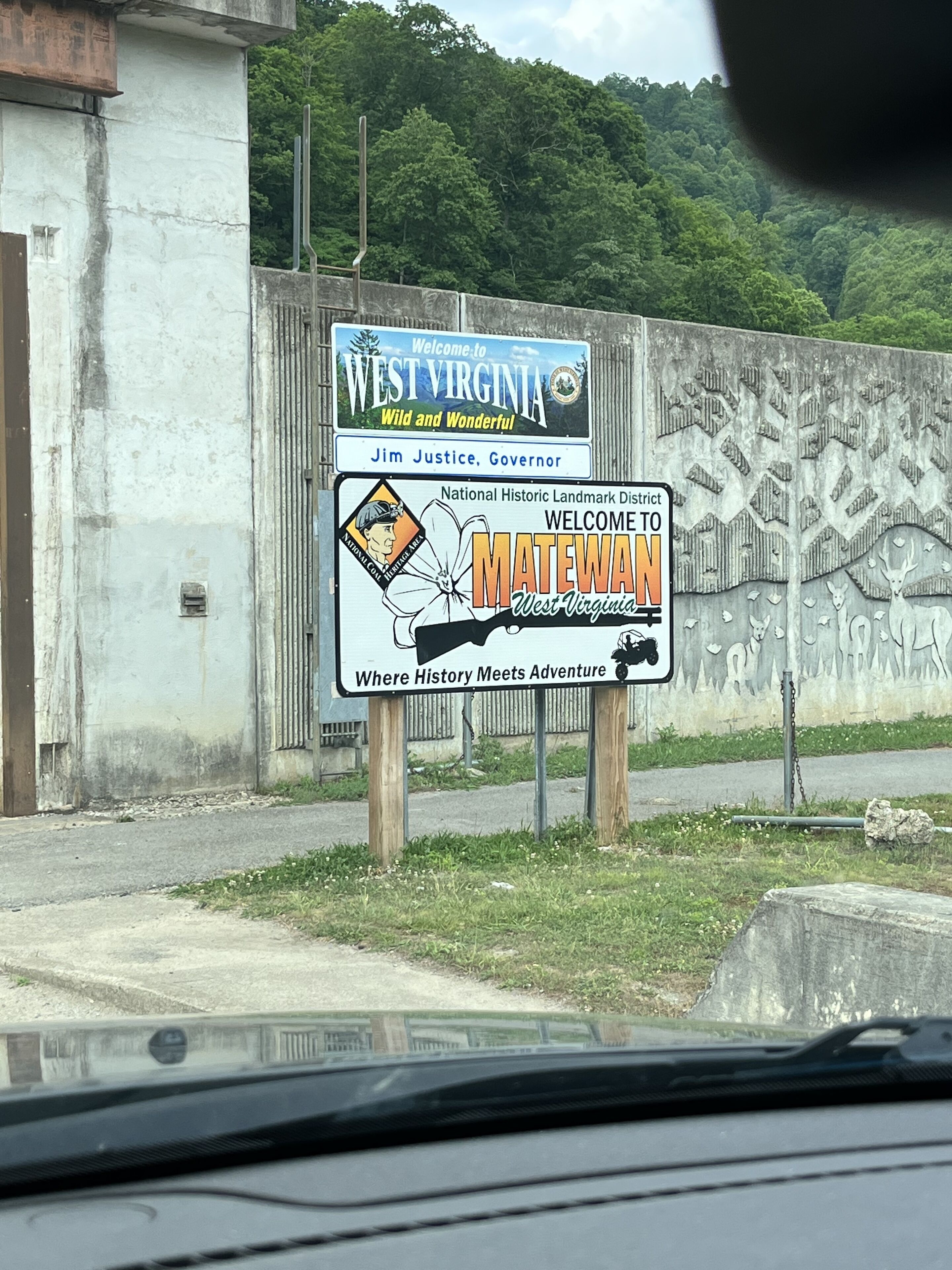 Letrero de bienvenida a Virginia Occidental y Matewan, Virginia Occidental, con un mural de ciervos y una motocicleta.