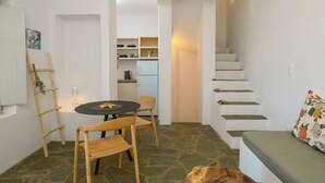 A compact living space with a dining area, a staircase, and a kitchenette. - Amorgos Elegant Houses, Villa 2 (Amorgos)