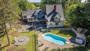 Uma casa grande com piscina, lareira e área de estar ao ar livre.