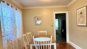 A dining area with a wooden table and chairs, a ceiling light, and a door leading to another room. - Country Comfort near City Conveniences (Saint Paul)