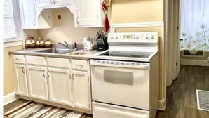 A compact kitchen with white cabinetry, a stove, and a sink. - Country Comfort near City Conveniences (Saint Paul)