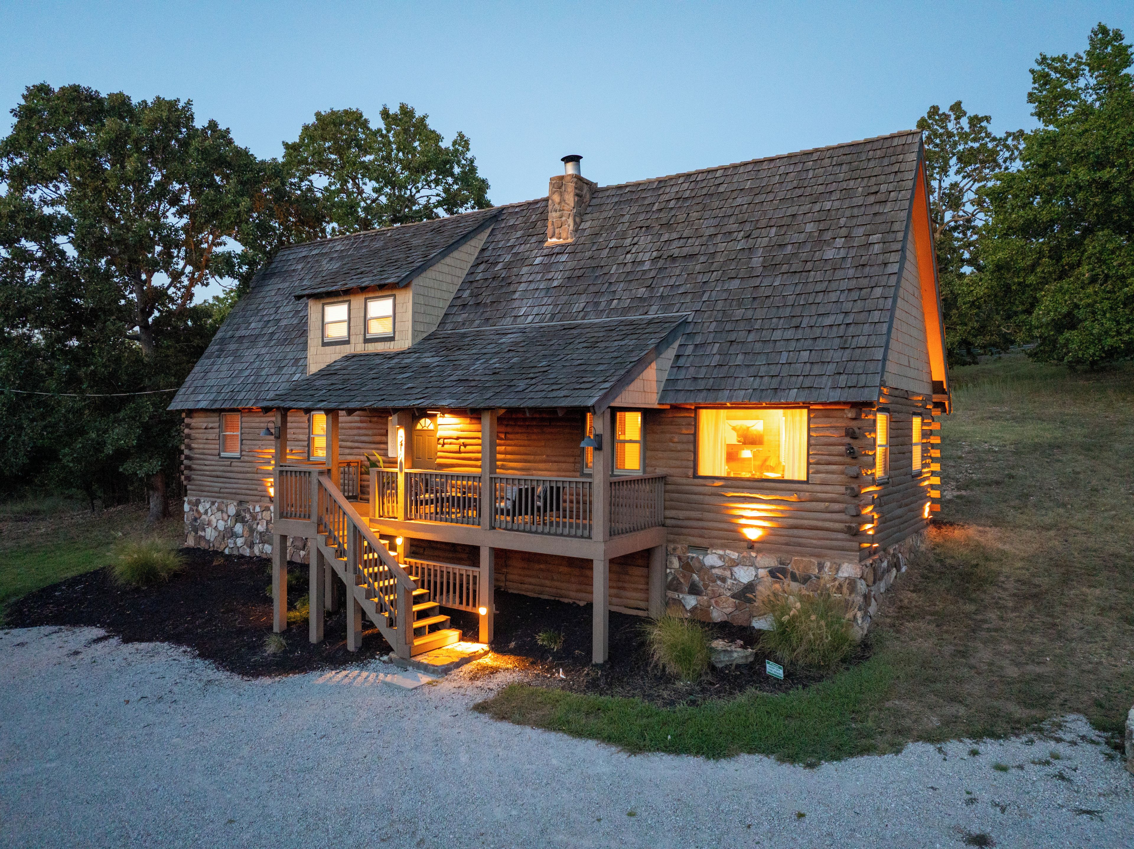 Une cabane en rondins avec un porche, un escalier et une cheminée.
