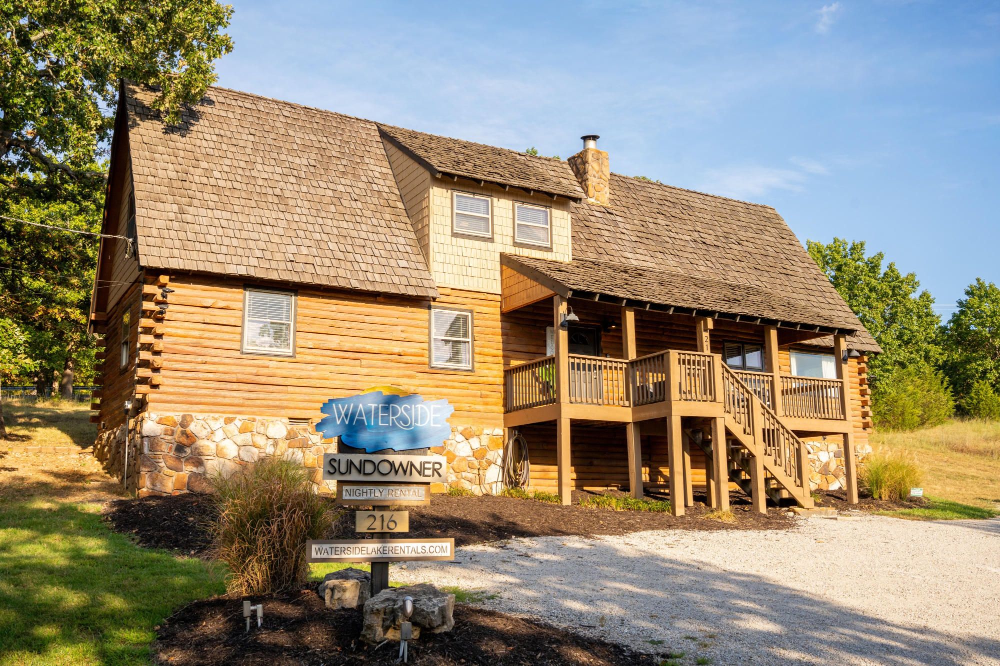 A wooden cabin with a stone foundation, a porch, and a sign indicating it is a sundowner rental.