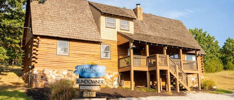 A wooden cabin with a stone foundation, a porch, and a sign indicating it is a sundowner rental.