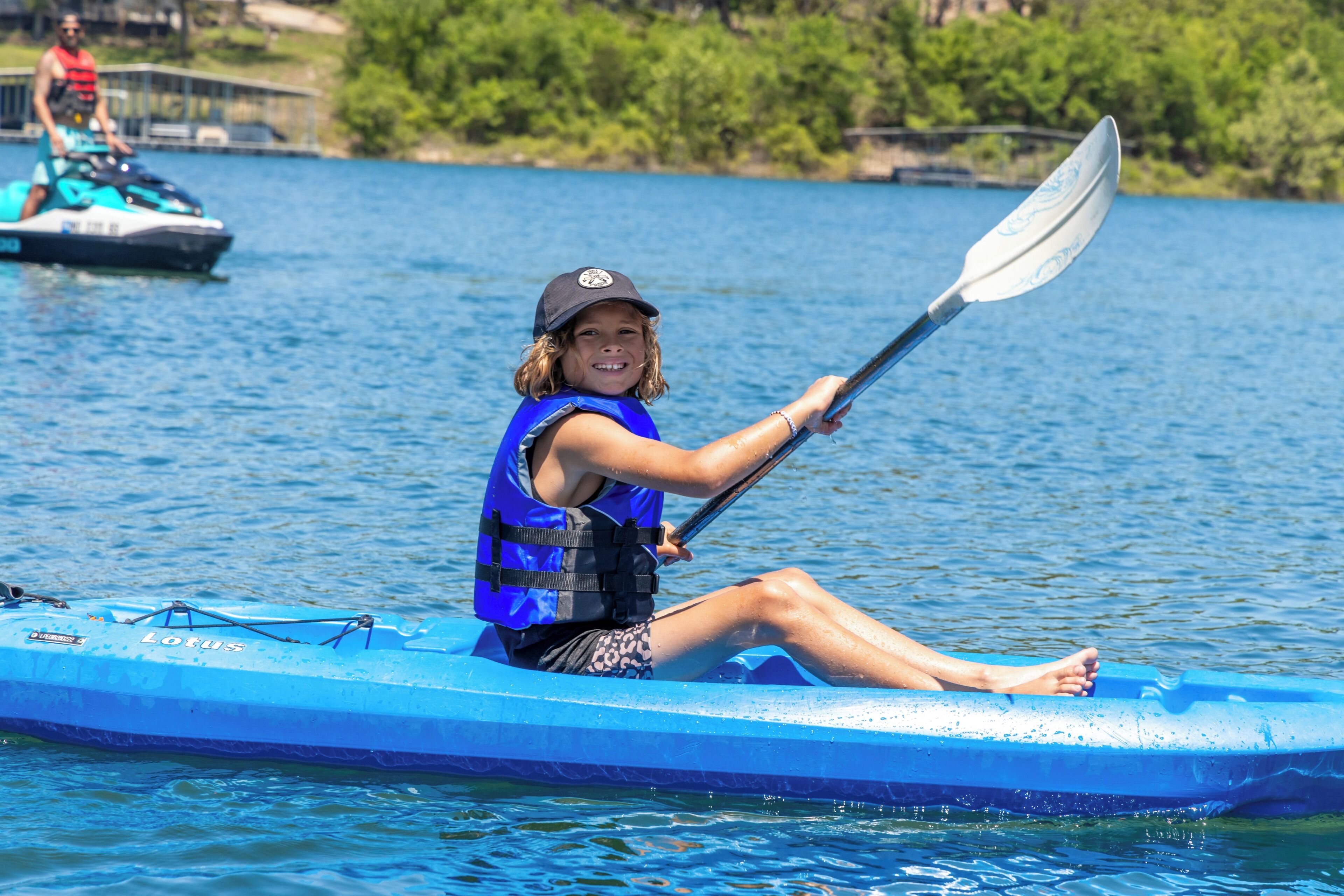 A person kayaking on a blue watercraft.