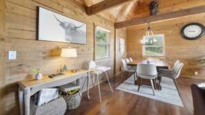 A wooden interior with a dining table, chairs, a clock, and a framed picture of a bull. - Lakeside Resort Cabin Steps to Table Rock Lake - Minutes to SDC! (Branson)