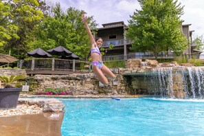 A person jumping into a pool with a waterfall in the background. - Lakeside Resort Cabin Steps to Table Rock Lake - Minutes to SDC! (Branson)