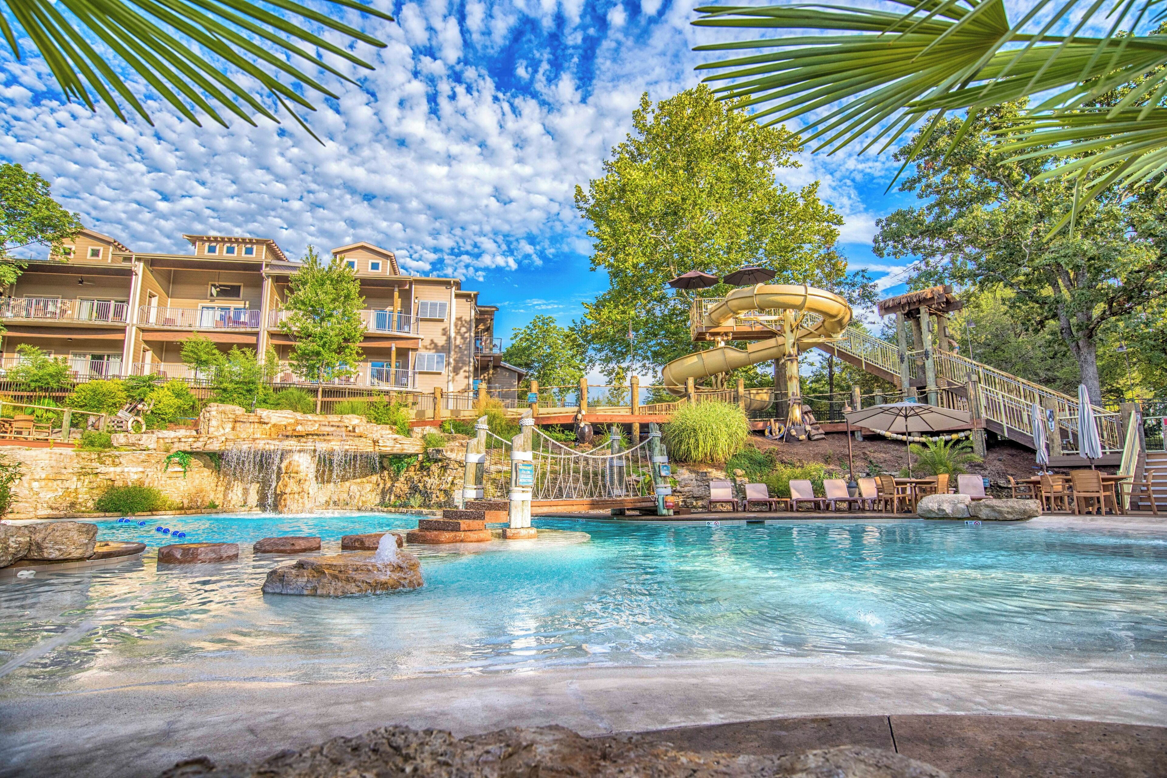 A resort with a pool, a water slide, and a view of the surrounding buildings.