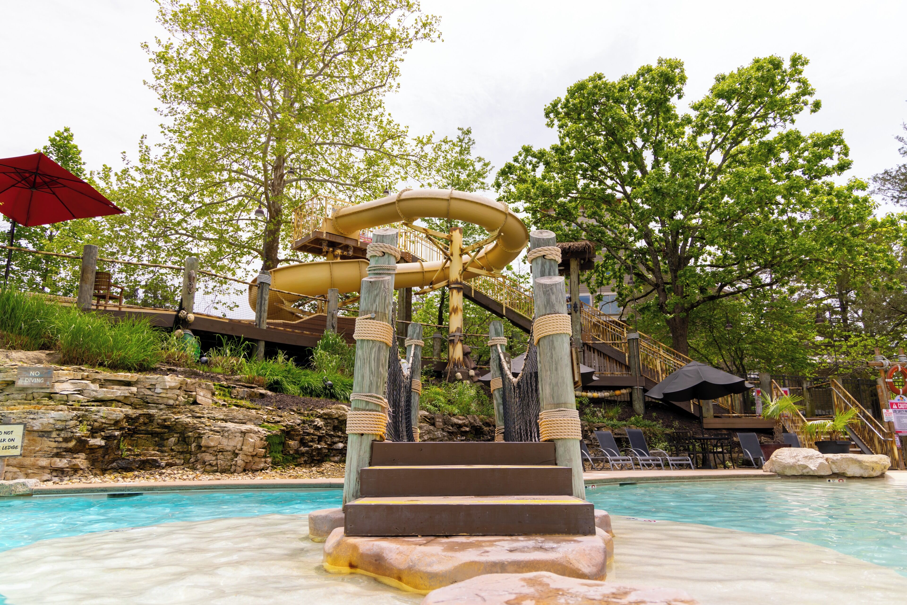 A water slide with a rope ladder leading to a pool.