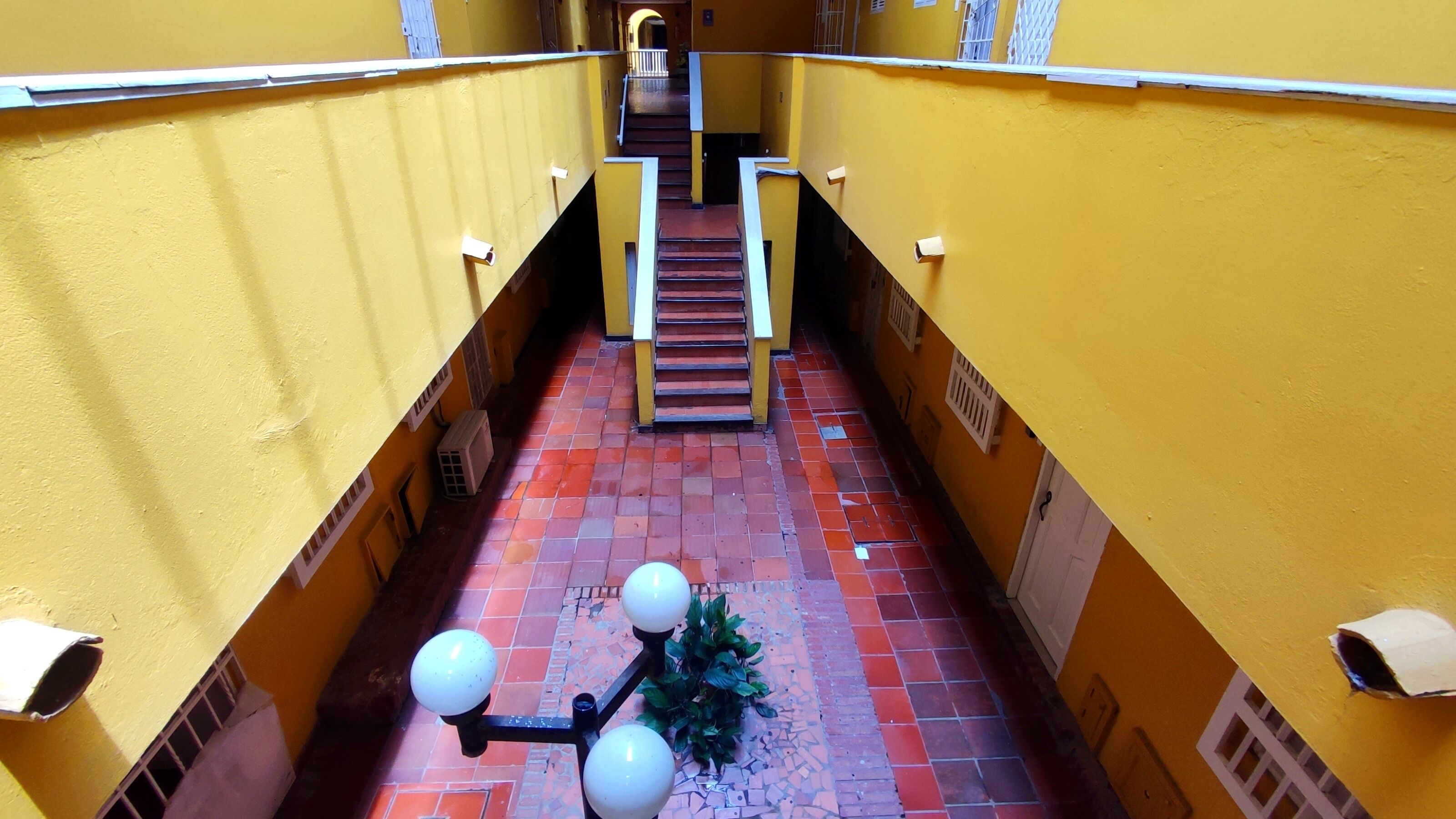 A narrow corridor with yellow walls, a tiled floor, and a staircase leading upwards.