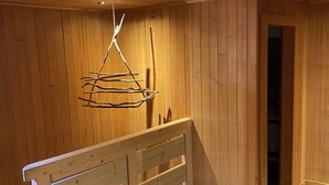 Un interior de madera con un banco, una lámpara colgante y un acceso a otra habitación.