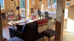 Interior de una cabaña de madera con comedor, sofá y banco.