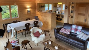 Un interior de cabaña acogedor con comedor, sala de estar con sofá de cuero y zona de cocina.