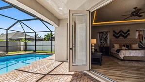 A modern home with a swimming pool, a bedroom with a bed and nightstand, and a living area with a sofa and lamp.