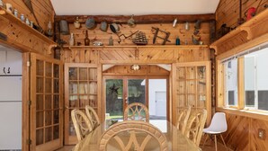 Ein Holzblockhaus-Innenraum mit Esstisch, Stühlen und Küchenzeile, einschließlich Holzschränken und verschiedenen Küchengeräten.