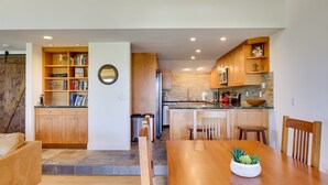 Une cuisine moderne avec des meubles en bois, un coin repas doté d’une table en bois et une bibliothèque intégrée.