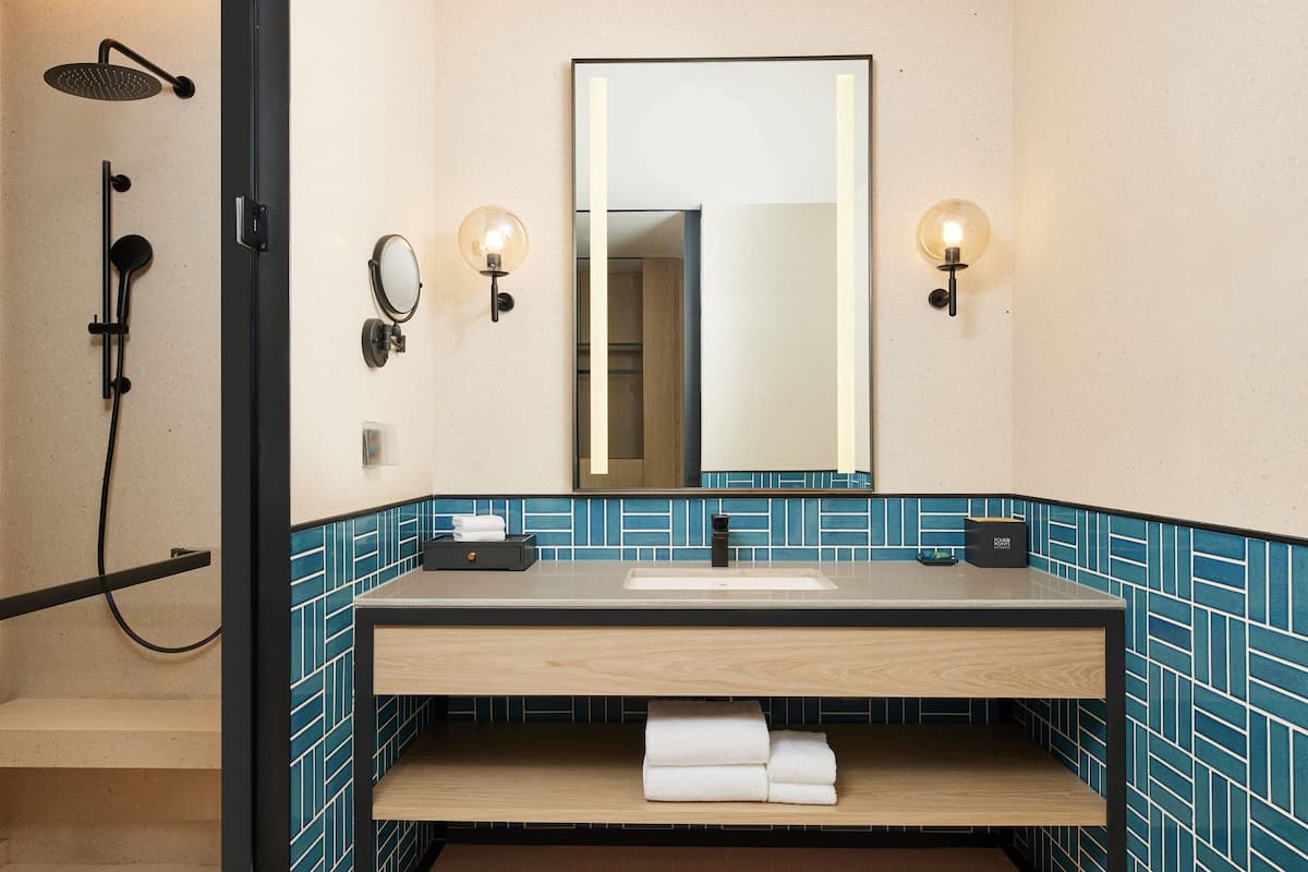 A bathroom with a shower, sink, and mirror.