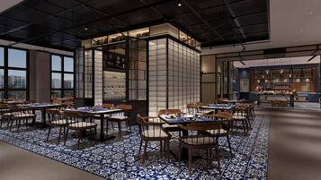 Un restaurante moderno con techo alto, ventanas amplias y suelo con estampado azul y blanco. Mesas y sillas dispuestas para comer.