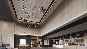 A spacious lobby with a high ceiling, hanging light fixtures, and a central seating area.