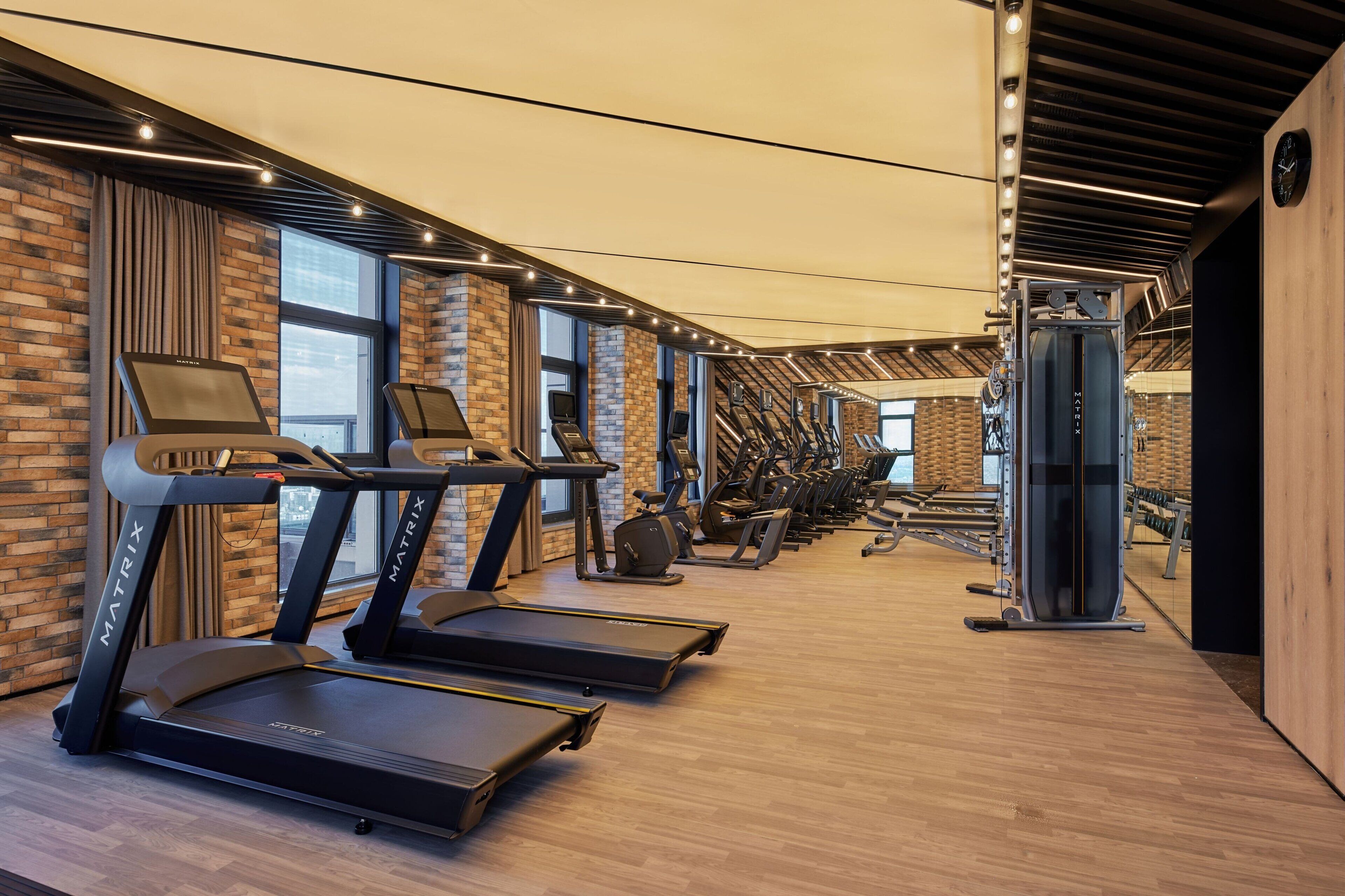 A modern gym with treadmills, elliptical machines, and weight equipment.