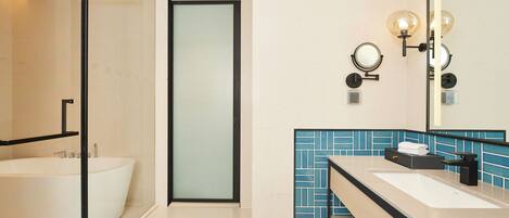 Un baño moderno con una bañera independiente, un espejo grande y un tocador con lavabo y perchero para toallas.