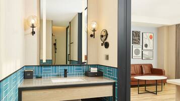 A modern bathroom with a large mirror, two wall sconces, a sink, and a towel rack.