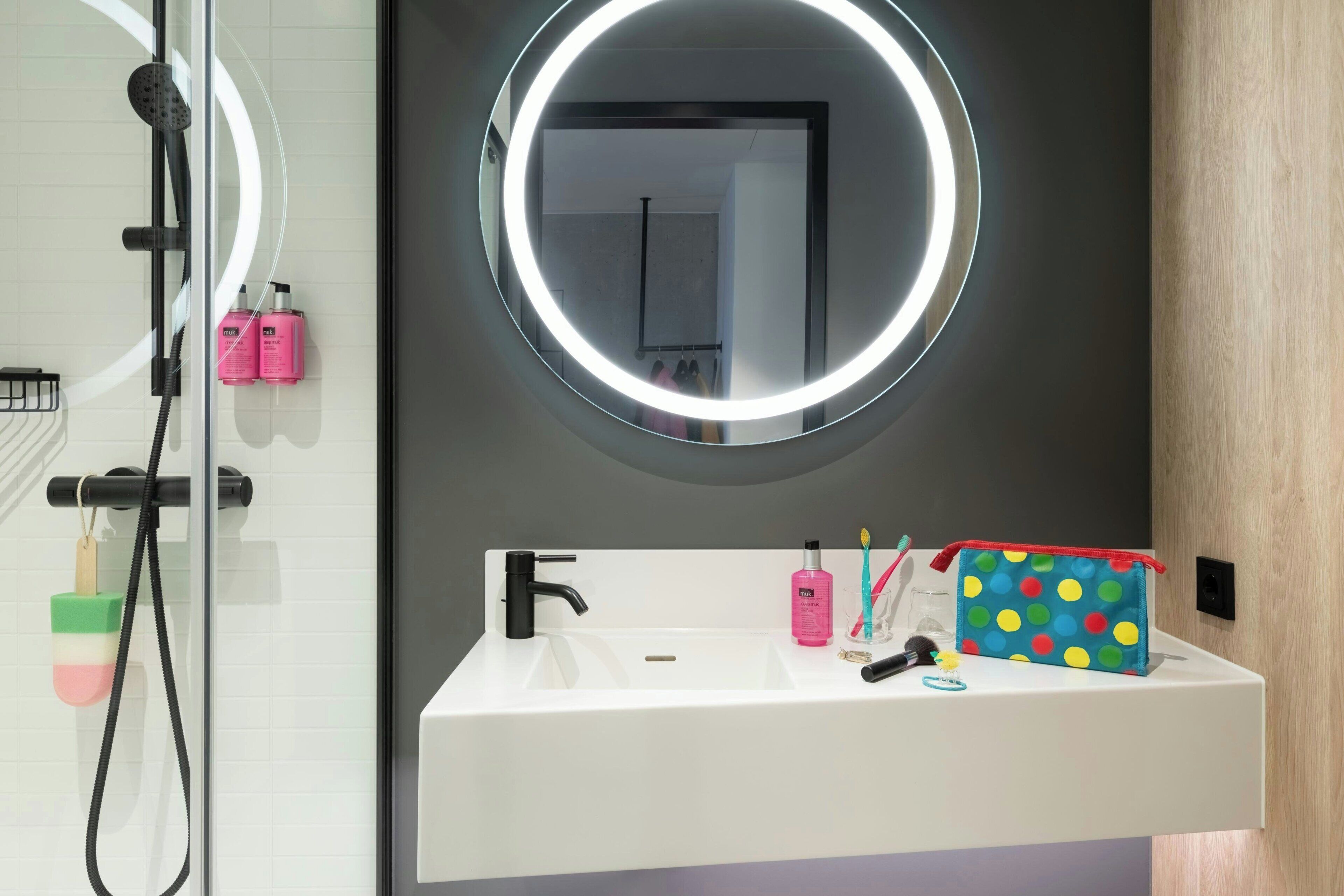 Un baño con espejo, lavamanos y ducha.