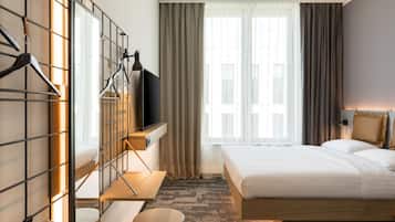 Une chambre d’hôtel équipée d’un lit, d’une télévision, d’un bureau et d’une armoire.