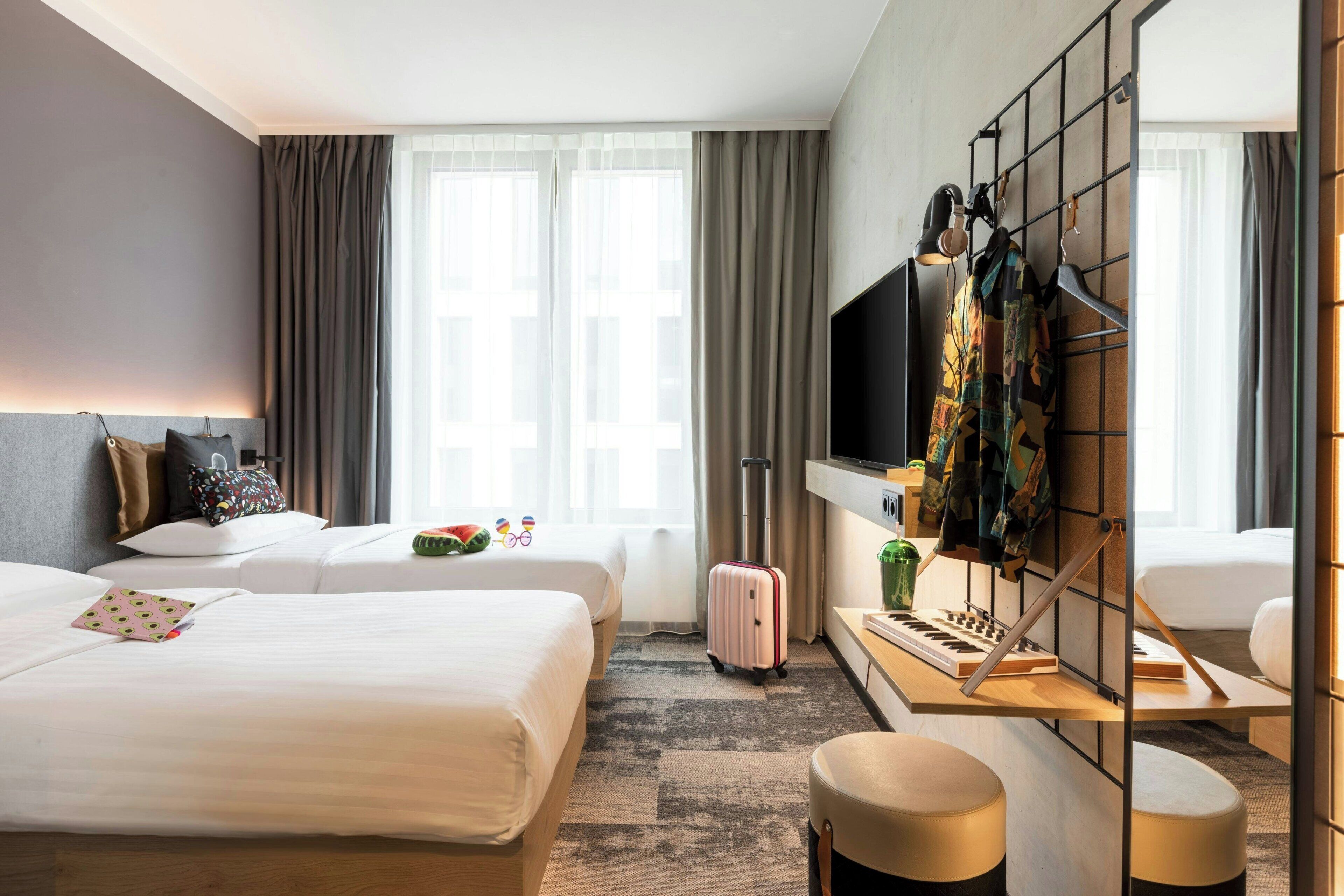 A hotel room with two beds, a desk with a computer, a TV, and a wardrobe.