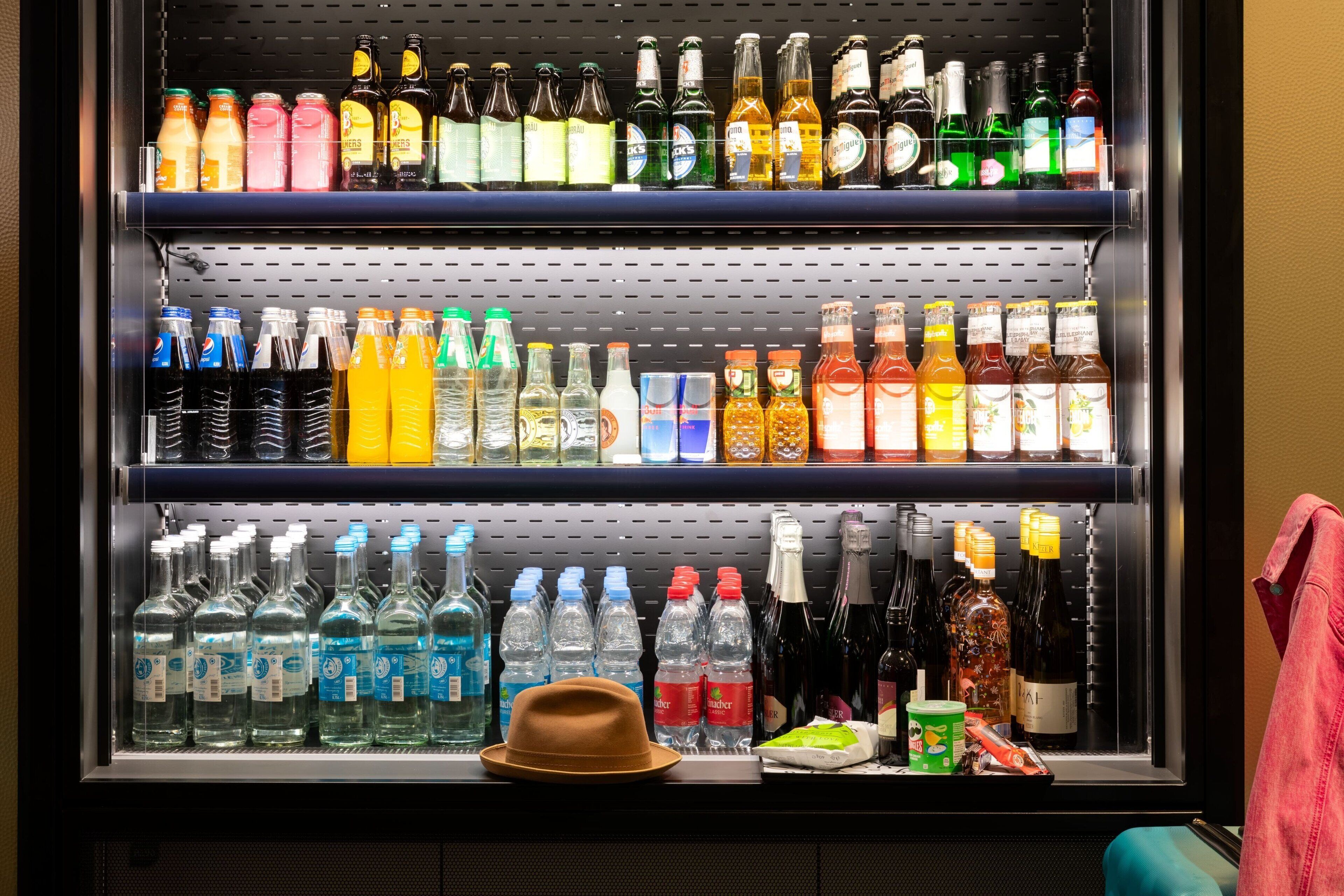 A beverage refrigerator stocked with various drinks, including sodas, juices, and alcoholic beverages.